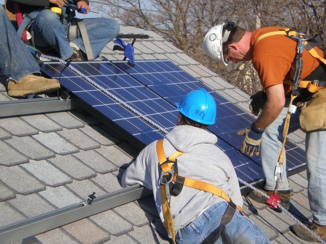 workers installing solar panels on a roof