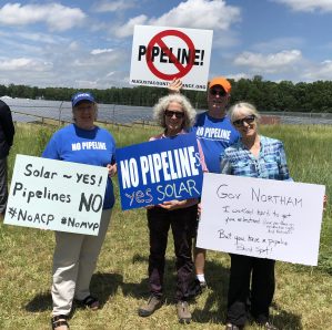 gas pipeline protesters standing in front of solar panels