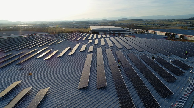 workers complete a rooftop solar array on a warehouse